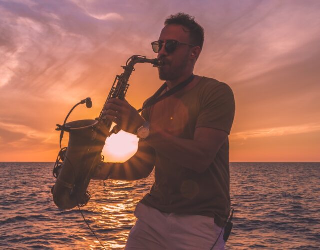 Saxophone Player in front of golden mediterranean sunset on the sea