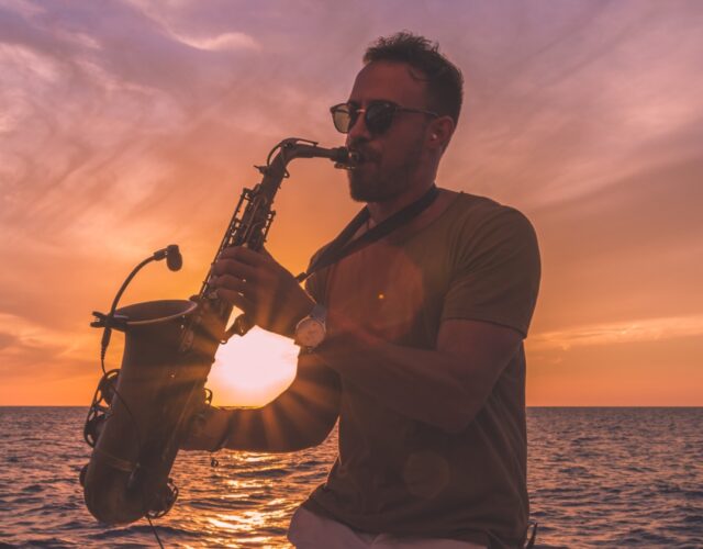 Saxophone Player in front of golden mediterranean sunset on the sea