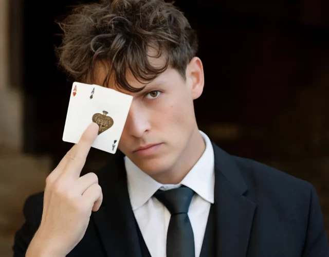 A Magician wearing a suit proudly holds a card, showcasing it with a friendly expression