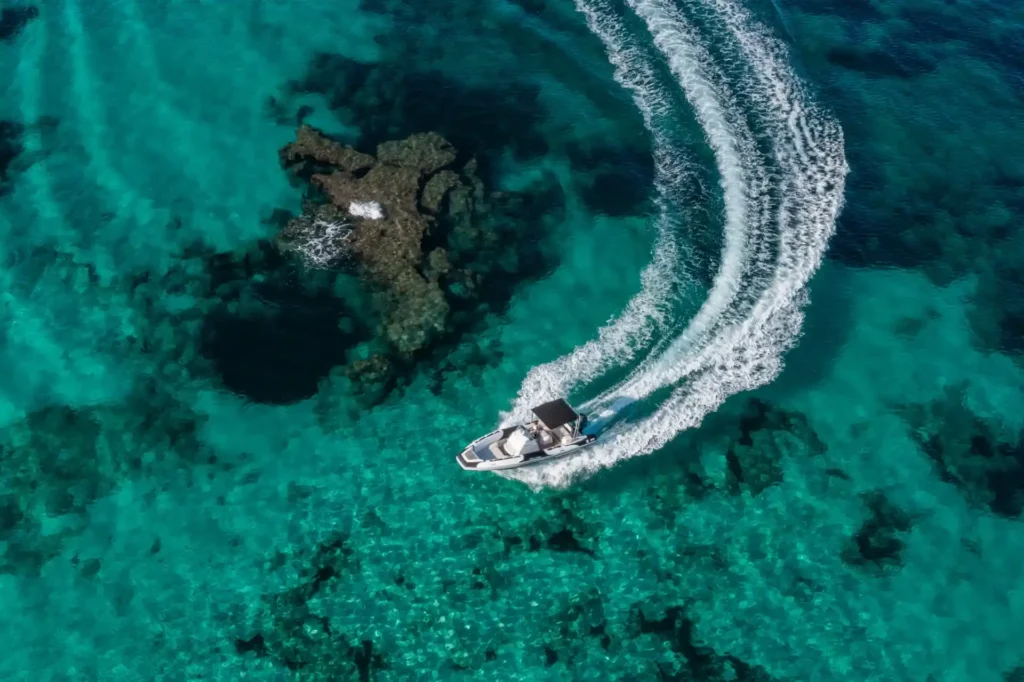 Ibiza excursions, a boat glides through the ocean, leaving a distinct wake behind as it navigates the tranquil waters.